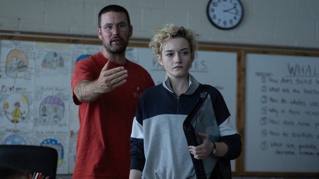 Zach Cregger stands behind Julia Garner, giving direction. They are in a classroom, and Garner is looking in the direction Cregger is gesturing.