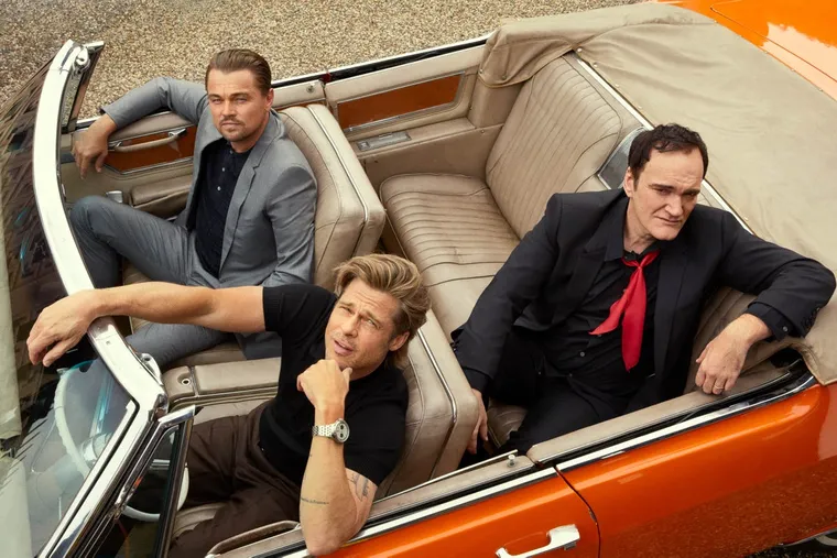 A promotional image from Once Upon a Time in Hollywood. Brad Pitt, Leonardo DiCaprio, and Quentin Tarantino sit in a red sports car, shot from above.
