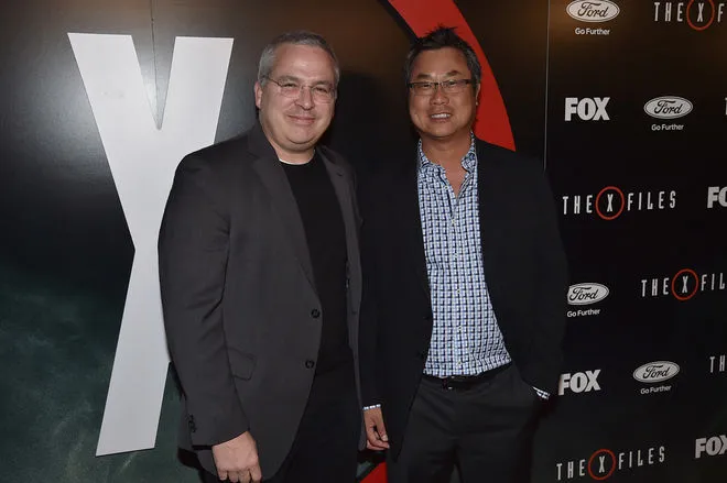 Glen Morgan and James Wong, both in suits, on the red carpet at an X-Files event.